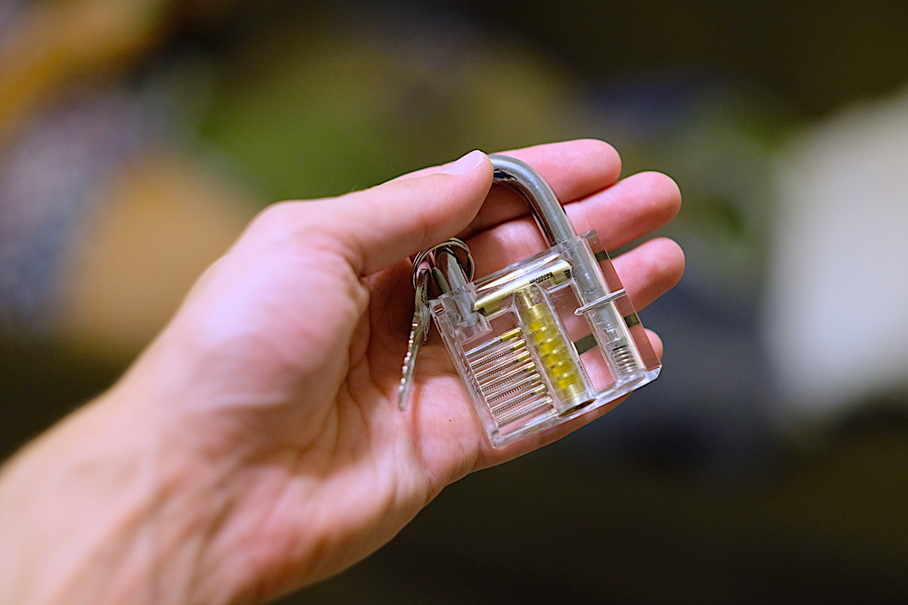 hand holding a transparent lockpicking practice lock